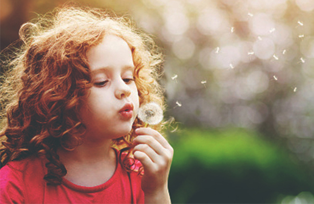 girl blowing a dandelion