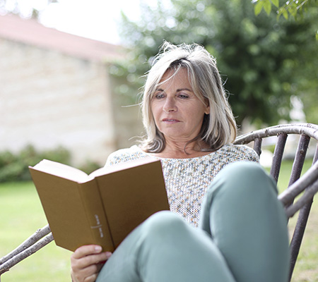 Image of elderly person reading book outside